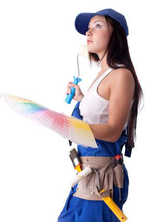 Young woman in overalls with a color guide and paintbrush on a white background.の写真素材