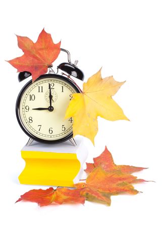 Alarm clock, autumn leaves and stacked  blank papers on a white background.の写真素材