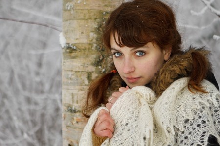 Girl with a downy shawl in a winter forest.の写真素材