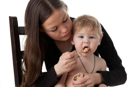 Young mother feeds  her baby on a white background. Happy family.
