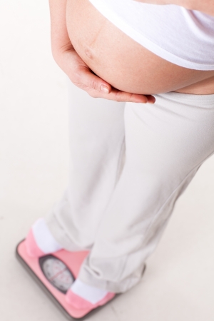 Young  pregnant woman with scales on a white background.の写真素材