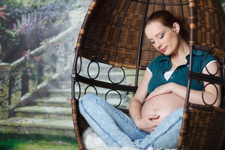 Pregnant woman sits on swing at home.の写真素材