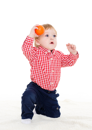 Little sweet boy plays with small orange ball on a white background.の写真素材