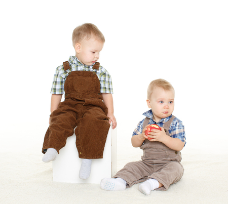 Two little boys with fresh apple sit on a white background. Healthy food.の写真素材