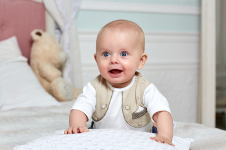 Happy little baby boy is lying on stomach in the room on the soft bed. Six monthの写真素材