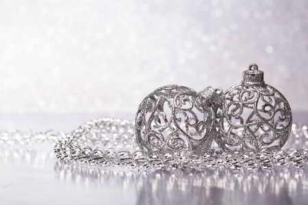 Christmas decoration with silver balls and garlands lying on a silvery background. New year and Christmas background with copy space for text. Greeting card.の写真素材