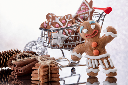 Shopping trolley with gingerbread cookies and christmas decorations standing on a white  background with reflection. Christmas and New Year sale.の写真素材