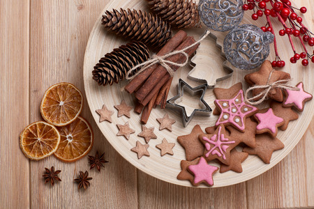 Christmas decor with gingerbreads lying on a wooden plate on a wooden background. Top view. For greeting card.の写真素材
