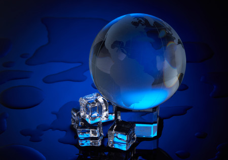 Globe and melting ice cube on a blue background with water drops. Concept of global warming.  Protecting environment.の写真素材
