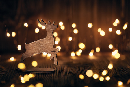 Wooden deer  on a wooden background with LED lights garland. Christmas decoration.の写真素材