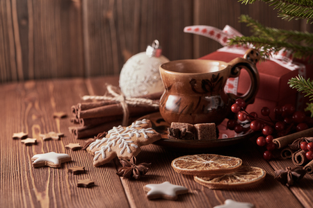 Cup of coffee, gingerbread cookies, gift box, fir tree branches with decorations on a wooden brown background.  Christmas and New Year treat.の写真素材