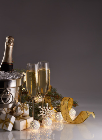 Still life with champagne bottle standing in a bucket with ice, two full champagne flutes, LED lights garland  and Christmas ornaments. Christmas and New Year celebration backgroundの写真素材