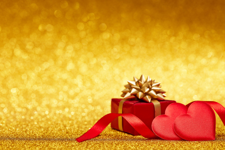 Two decorative hearts and gift box on a glittering gold background with copy space. Valentine's Day card. Design element for romantic greeting card, wedding invitation,の写真素材
