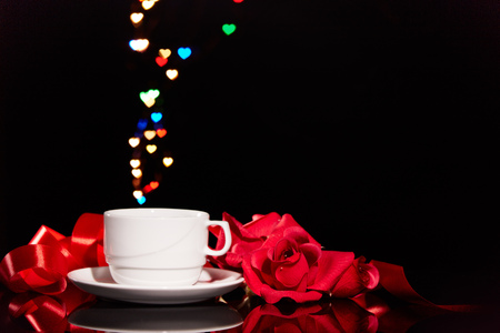 Still life with cup of coffee, red roses on  black background with heart-shaped bokeh. Copy space. Valentine's Day setting table. Design element for romantic greeting card, festive menu of cafeの写真素材