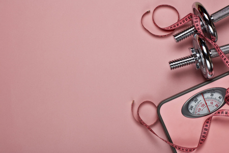 Female fitness still life. Dumbbells and scales  on pink background. Mockup. Planning of diet and trainings. Top view with copy space. Healthy lifestyle concept. Slimmingの写真素材
