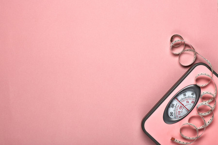 Female fitness still life. Scales and measuring tape on pink background. Mockup. Planning of diet and trainings. Top view with copy space. Healthy lifestyle concept. Slimmingの写真素材