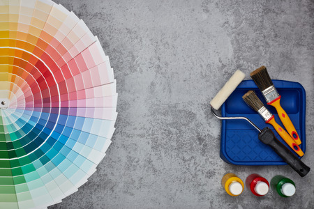Color palette guide and painting accessories ( paint brushes, roller and cans of paint) on grey background. Top view with copy space,  Concept of construction or design officeの写真素材