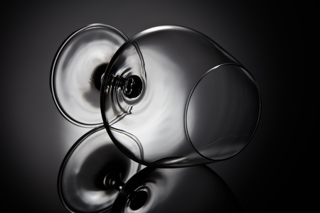 Silhouette of empty snifter glass (brandy snifter, brandy bowl, cognac glass, or balloon) on a black background with reflection. Glassware for aged brown spirits. Contour with gradient and highlightsの写真素材