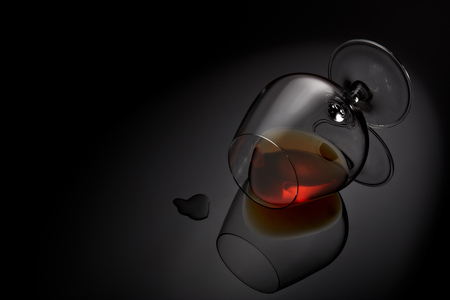 Snifter glass with cognac (brandy snifter, brandy bowl, cognac glass, or balloon) lying on a black background with reflection. Glassware for aged brown spirits. Contour with gradient and highlightsの写真素材