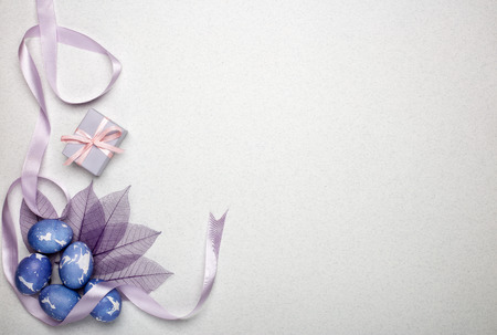 Colored easter eggs, gift box, decorative purple leaves on a lilac  background. Top view with copy space. Greeting card, Easter backgroundの写真素材