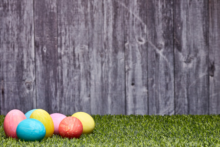 Colored easter eggs lying on a green grass on a grey wooden  background with copy space. Greeting...