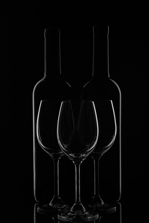Silhouette of two wine bottles and three empty wineglasses on a black background with reflection.  Contour with gradient and highlightsの写真素材