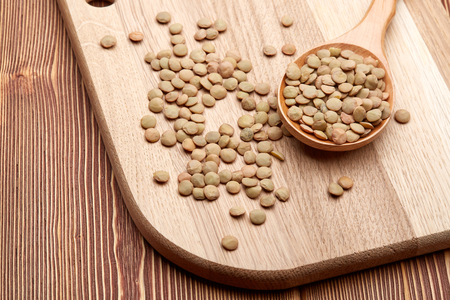 Dry lentils on wooden spoons lying on wooden background. Legumes. Top view.の写真素材