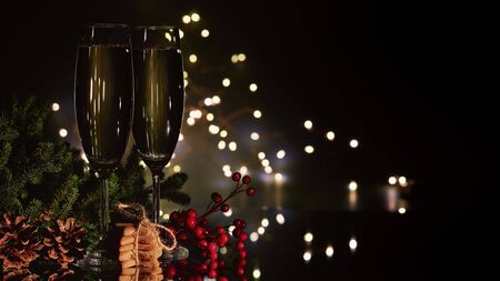 Two glasses with champange, fir tree branch with decorations and gingerbread cookies on a dark background with LED lights garland. New year and Christmas.の写真素材