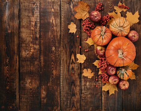 Festive autumn still life  with pumpkins, red apples, berries and leaves on dark  wooden background. Top view with copy space. Concept of autumn harvest, happy Thanksgiving  day or Halloween.の写真素材