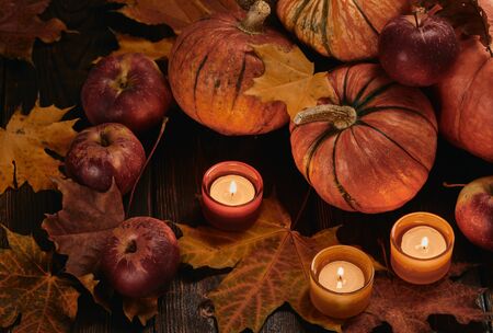 Festive autumn still life  with pumpkins, red apples, candles and leaves on dark  wooden background. Top view. Concept of autumn harvest, happy Thanksgiving  day or Halloween.の写真素材