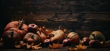 Festive autumn still life  with pumpkins, red apples and leaves on dark  wooden background with copy space. Concept of autumn harvest, happy Thanksgiving  day or Halloween.の写真素材