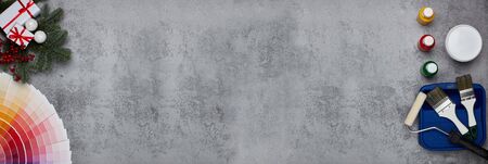 Color palette guide, paint brushes, roller, cans of paint, fir tree branch and gift boxes on grey background. Top view, copy space,  New Year and Christmas. Banner backgroundの写真素材