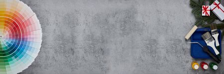 Color palette guide, paint brushes, roller, cans of paint, fir tree branch and gift boxes on grey background. Top view, copy space,  New Year and Christmas. Banner backgroundの写真素材