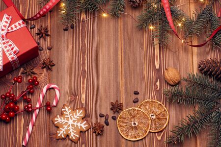 Christmas decor with fir tree branches, gingerbreads and gift box on a wooden background with copy space for text. Top view. For greeting card.の写真素材