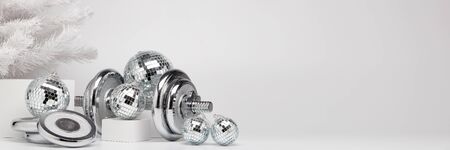 Dumbbells, Christmas fir tree and mirorr balls on white background with copy space. For design of advertising, web design. Christmas and New Year. Fitness, sport or healthy lifestyle concept.の写真素材