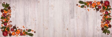 Festive still life with tangerines, nuts, spices and Christmas decorations on wooden light background. Top view with copy space. Christmas and New Year. Extra wide panorama banner backgroundの写真素材