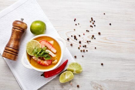 Delicious  fish cream soup with shrimps in white bowl served with spices and lime on light wooden background. Top view. Healthy food. Seafood menuの写真素材