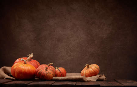 Festive autumn still life with pumpkins on dark wooden surface on brown background with copy space. Concept of autumn harvest, happy Thanksgiving  day or Halloween.の写真素材