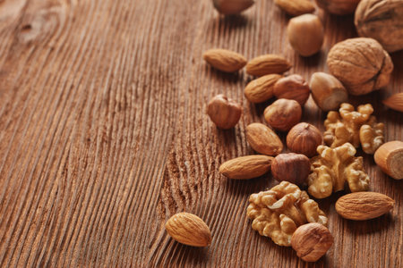 Different kinds nuts. Various varieties of  whole nuts and kernels on brown textured wooden...