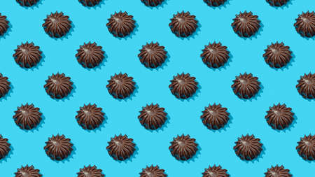 Food pattern background. Bright food pattern of chocolate marshmallows on blue background. Top view