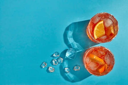 Cocktail. Fresh orange juice. Two glasses with cool beverages, sliced oranges and ice on blue...