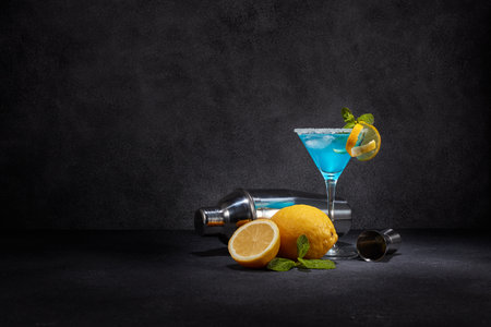 Glass with blue curacao cocktail, fresh mint and lemon, bar tools on dark grey background with copy space. Bar. Party. Blue cocktail.の写真素材