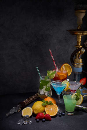 Hookah and cocktails set. Glasses with various cold  beverages, fruits, shisha and bar tools on dark...