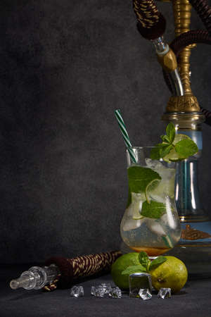Hookah (shisha) and glass of Mojito cocktail with lime and ice on dark grey background with copy space. Weekend or holiday party. Hookah bar, nightclubの写真素材