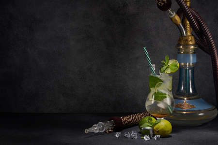 Hookah (shisha) and glass of Mojito cocktail with lime and ice on dark grey background with copy space. Weekend or holiday party. Hookah bar, nightclubの写真素材