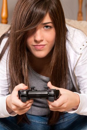 Young girl concentrating playing video-games close-up on sofa at homeの写真素材