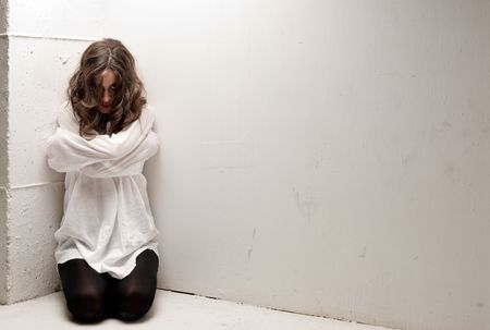 Young insane woman with straitjacket on knees looking at camera の写真素材