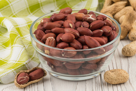 Peanut in a glass bowl on the old wooden table.  Selective focus.