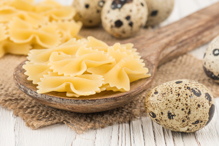 Pasta in a wooden spoon and an old white wooden table. Selective focus.の写真素材