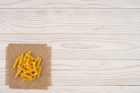 Pasta on sacking and an old white wooden table. Top view.の写真素材